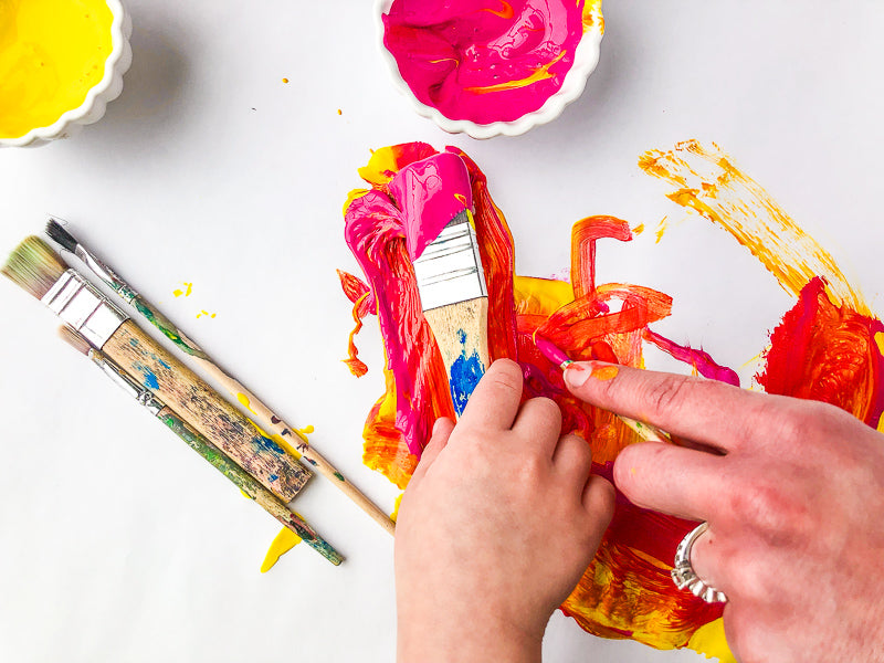 A child's hand and a mother's hand painting together with image text "Create Togetherness."